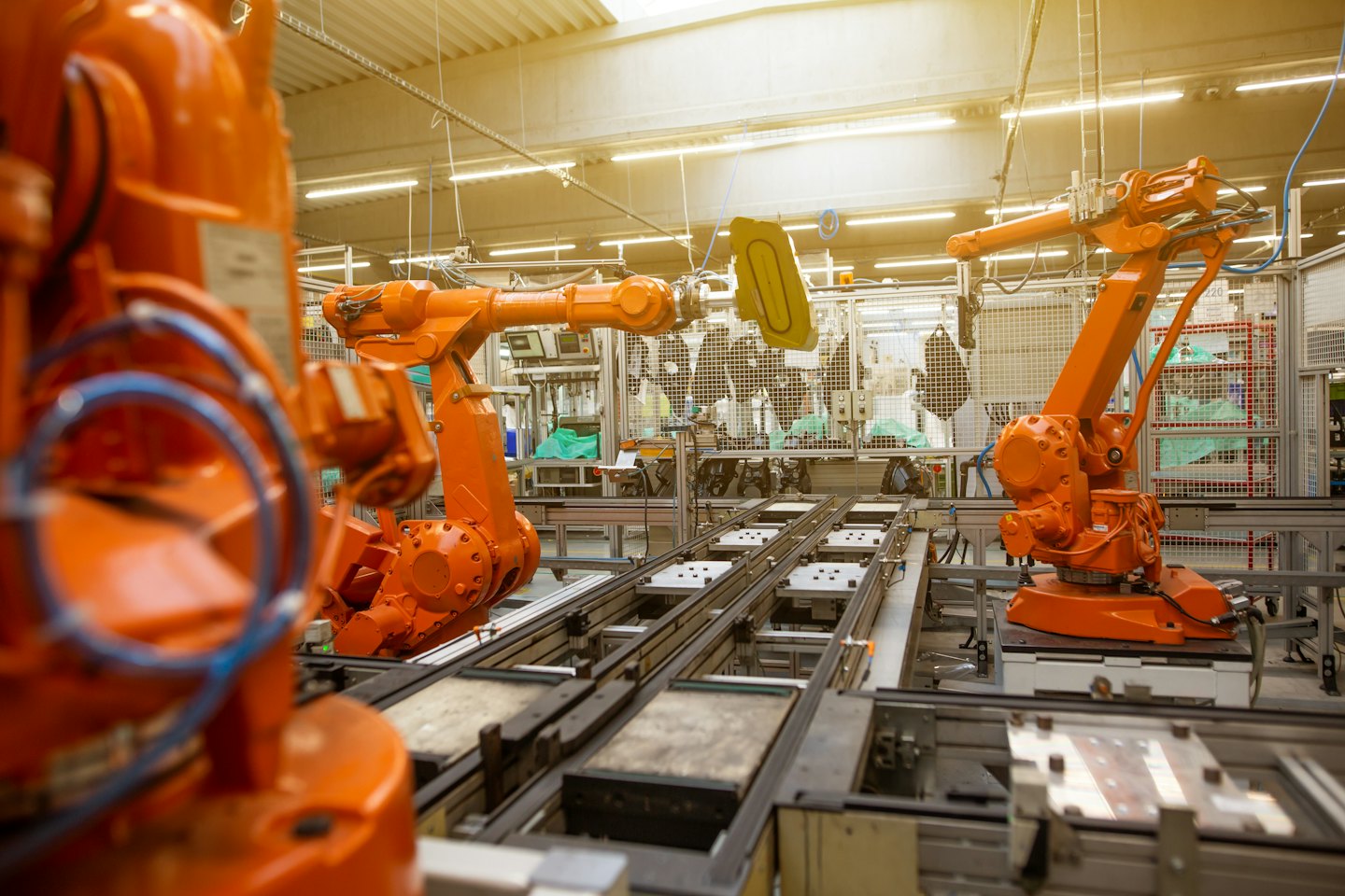Des bras robotisés assemblent des composants dans un atelier d'usine lumineux.